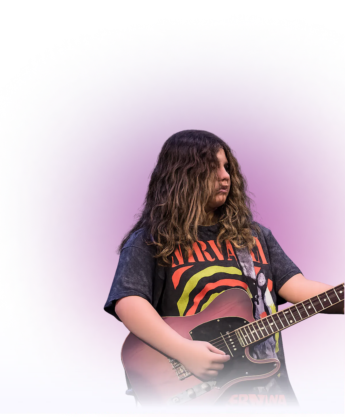 Young musician with long wavy hair playing an electric guitar while wearing a graphic band T-shirt.